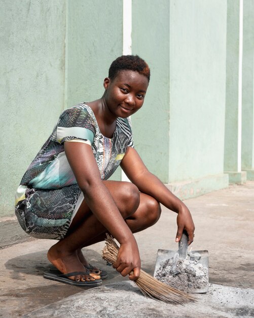 Mujer africana de tiro completo barriendo