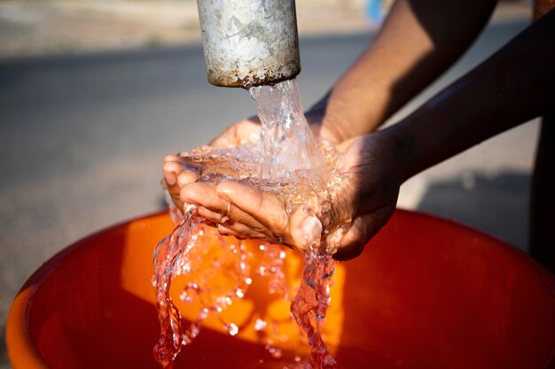 Mujer africana vertiendo agua en un recipiente al aire libre