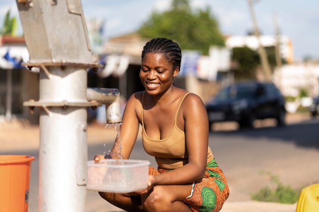 Mujer africana vertiendo agua en un recipiente