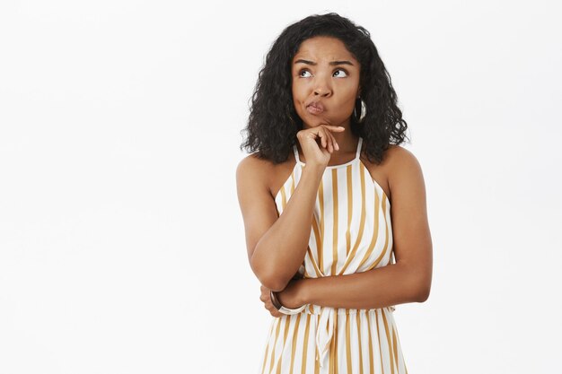 Mujer afroamericana atractiva inteligente y creativa insegura con un mono amarillo rayado de moda sonriendo