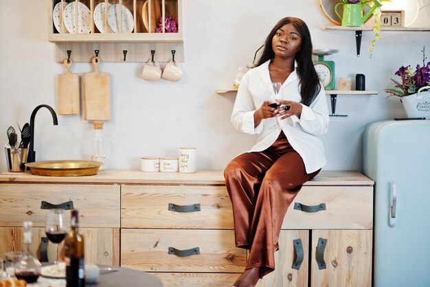 Mujer afroamericana bebiendo vino en la cocina en su cita romántica