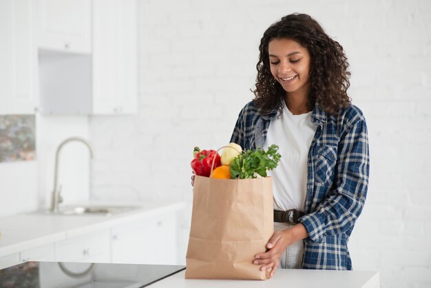 Mujer afroamericana con bolsa de verduras