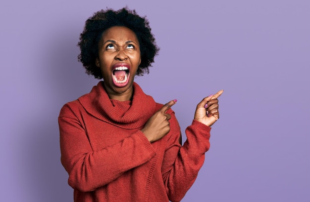 Foto gratuita mujer afroamericana con cabello afro apuntando con los dedos hacia un lado enojado y enojado gritando frustrado y furioso gritando con ira mirando hacia arriba