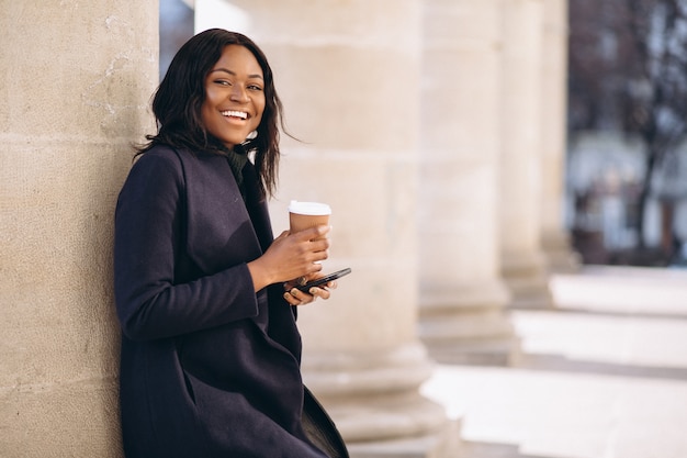 Mujer afroamericana con café tomando teléfono