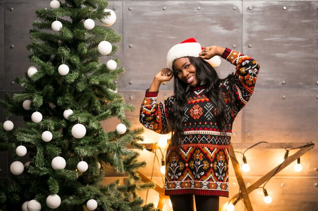 Mujer afroamericana colgando juguetes en un árbol de Navidad