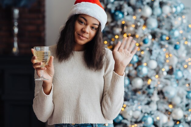 Mujer afroamericana con copa de champán en casa. celebración de Navidad