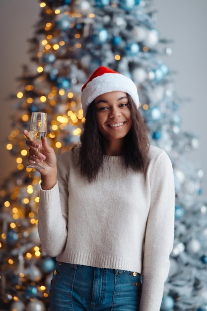 Mujer afroamericana con copa de champán en casa. celebración de Navidad