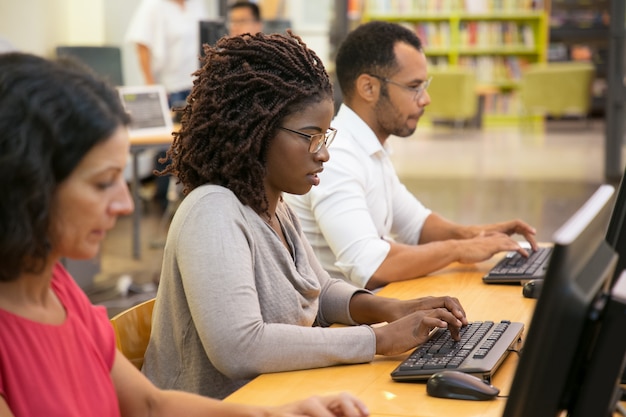 Mujer afroamericana enfocada escribiendo en el teclado de la computadora