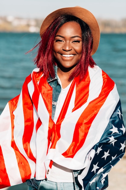 Mujer afroamericana envolviendo en bandera de Estados Unidos
