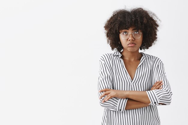 Mujer afroamericana guapa triste y molesta que se siente triste y lamentando los planes para la noche arruinada frunciendo los labios mirando hacia arriba y cruzando las manos sobre el pecho por la decepción