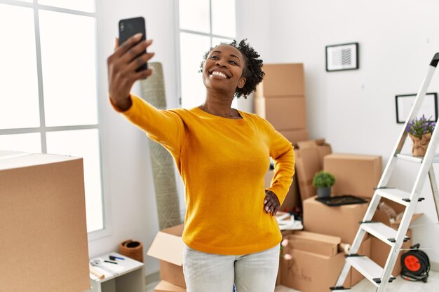 Mujer afroamericana hace selfie por teléfono inteligente de pie en el nuevo hogar