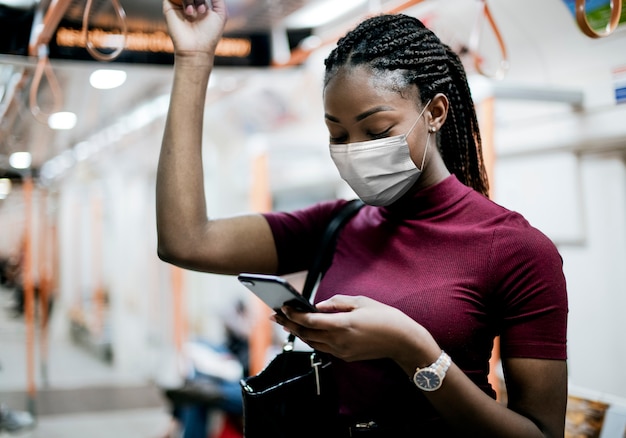 Mujer afroamericana con máscara en el autobús mientras usa el transporte público en la nueva normalidad