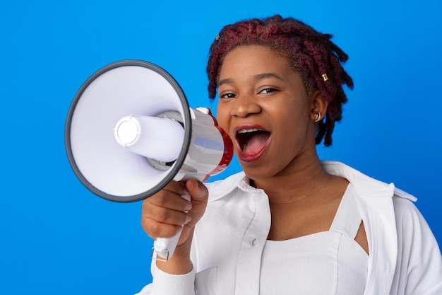 Mujer afroamericana con megáfono contra el fondo azul.