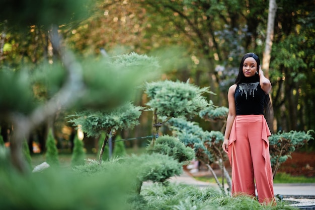 Mujer afroamericana de moda en pantalones de melocotón y blusa negra posan al aire libre