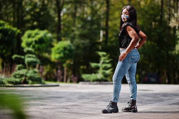 Mujer afroamericana de moda usa mascarilla hecha a mano posando al aire libre Nueva vida normal