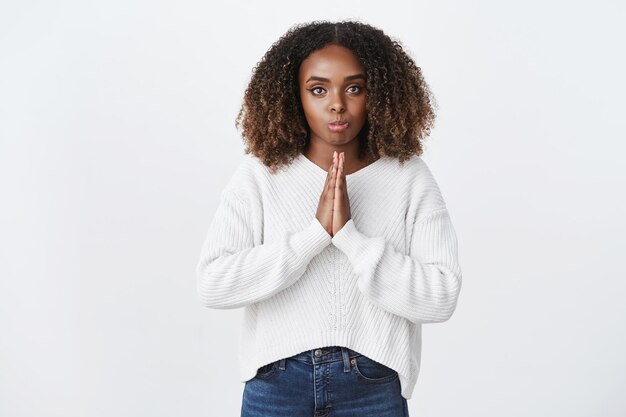 Mujer afroamericana mostrando cara tonta pidiendo favor haciendo pucheros labios expresión linda promesa ser buena prensa palmas juntas orar gesto frunciendo el ceño