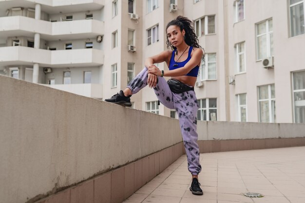 Mujer afroamericana negra en traje urbano de fitness deportivo en la azotea haciendo ejercicio