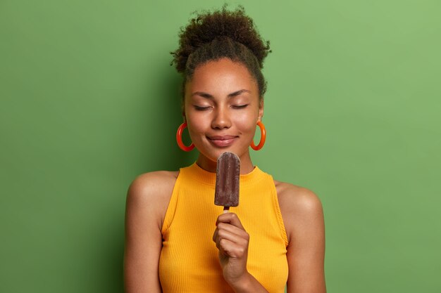 Mujer afroamericana positiva escalofríos con helado frío aislado