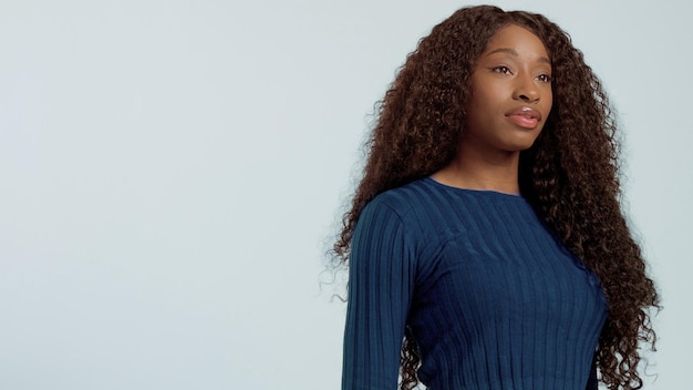 Mujer afroamericana de raza mixta negra de belleza con cabello largo y rizado y sonrisa perfecta mirando a la cámara y sonriendo en azul