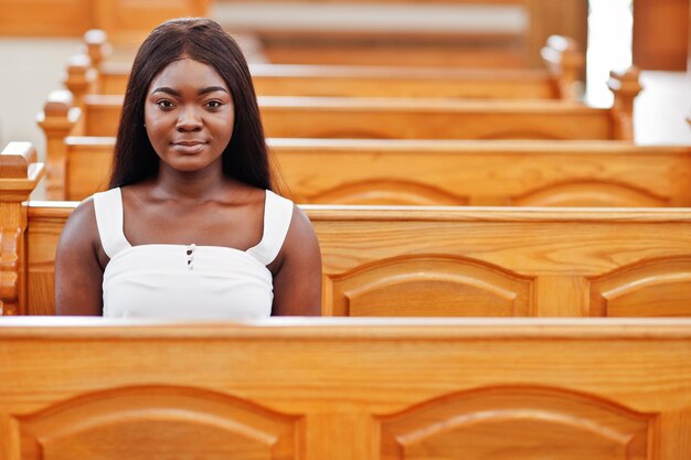 Mujer afroamericana rezando en la iglesia Los creyentes meditan en la catedral y el tiempo espiritual de oración Niña afro sentada en un banco