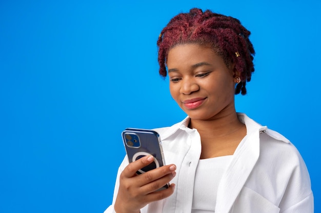 Mujer afroamericana con smartphone contra fondo azul.