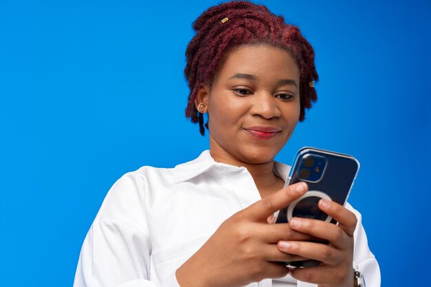 Mujer afroamericana con smartphone contra fondo azul.