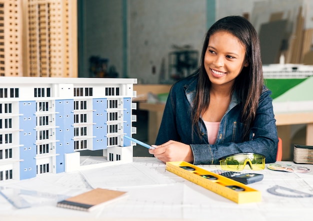 Mujer afroamericana sonriente mostrando modelo de edificio