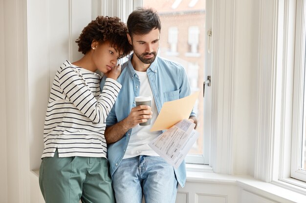 La mujer afroamericana y su marido caucásico barbudo discuten los términos del nuevo contrato con el empleado