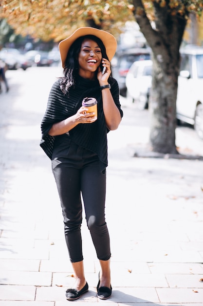Mujer afroamericana tomando café y hablando por teléfono
