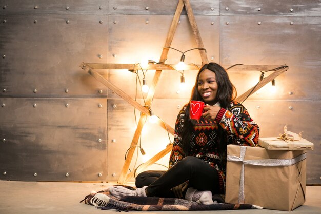 Mujer afroamericana tomando café en una víspera de Navidad