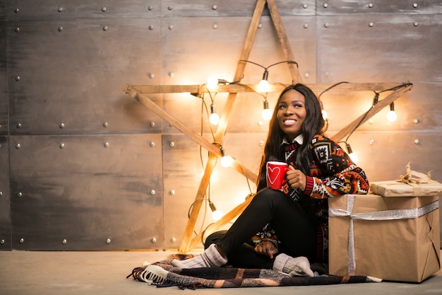 Mujer afroamericana tomando café en una víspera de Navidad