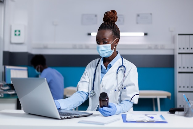 Mujer afroamericana con trabajo médico sosteniendo una botella de medicina