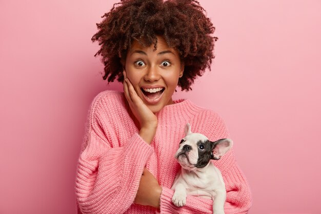 Mujer afroamericana vistiendo suéter rosa con cachorro