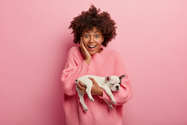 Mujer afroamericana vistiendo suéter rosa con cachorro