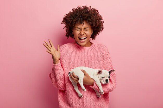 Mujer afroamericana vistiendo suéter rosa con cachorro