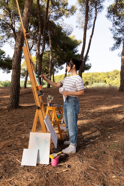 Foto gratuita mujer afuera en la naturaleza pintura sobre lienzo