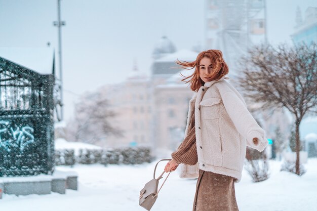Mujer afuera en nevando día frío de invierno