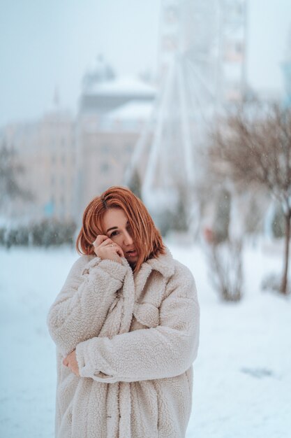 Mujer afuera en nevando día frío de invierno