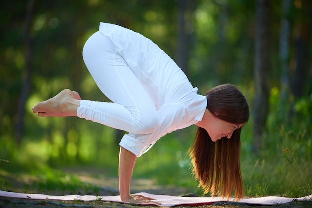 Mujer ágil sujetándose con las manos en pose de yoga