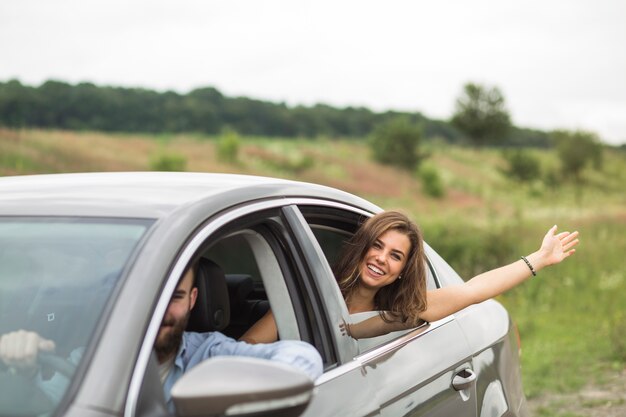 Mujer agitando su mano fuera de la ventana del coche