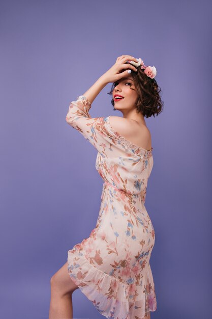 Mujer agraciada con piel pálida bailando. Modelo de mujer hermosa en vestido romántico de primavera mirando por encima del hombro.