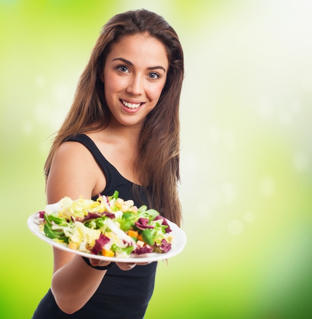 Mujer agradable con un plato de ensalada