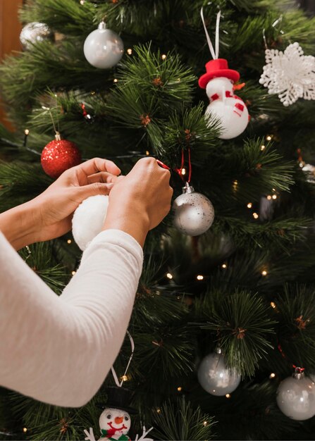 Mujer agregando juguetes al árbol de navidad