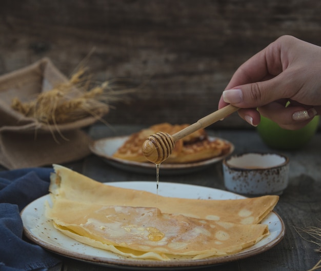 Mujer agregando miel a crepes.