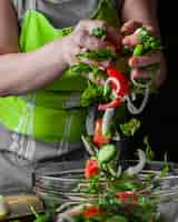 Foto gratuita mujer agregando verduras en vista lateral de ensalada de temporada