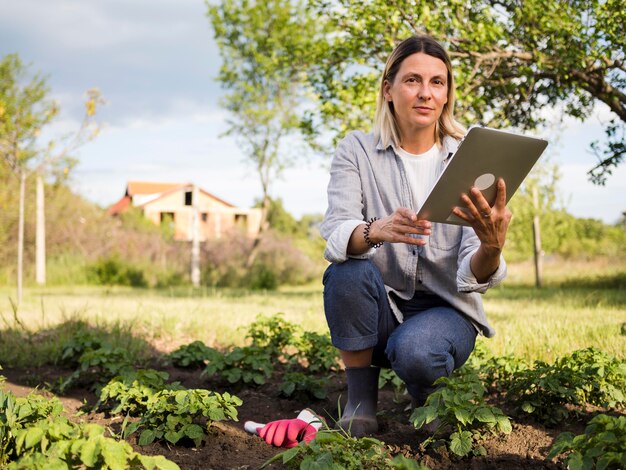 Mujer agricultora revisando su jardín con una tableta