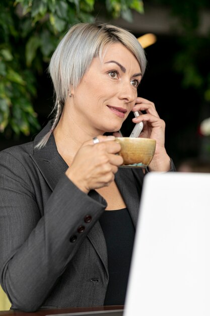 Mujer al aire libre disfrutando de un café y hablando por teléfono