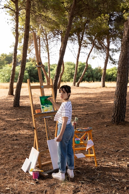 Foto gratuita mujer al aire libre en la naturaleza pintura paisaje sobre lienzo