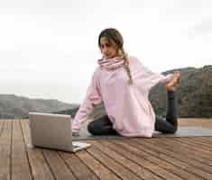 Foto gratuita mujer al aire libre con portátil haciendo yoga