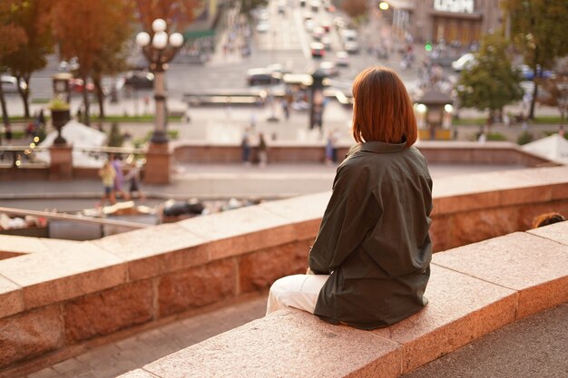 Mujer al atardecer con increíbles vistas a la ciudad, disfrutando de días cálidos, libertad, vibraciones positivas